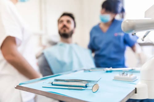 1 A man sitting in front of another man with dental tools.