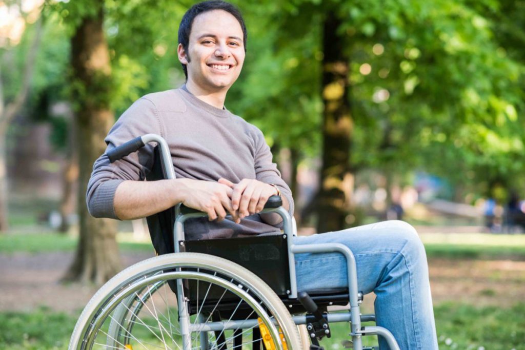 A man in a wheelchair smiling for the camera.